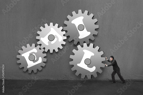 Photo: Businessman rolling a large concrete gear connect with others an Businessman rolling a large concrete gear connect with others an