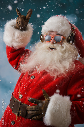 Photo: Santa Claus is listening to music in headphones outdoors at Nort Santa Claus is listening to music in headphones outdoors at Nort