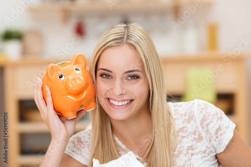 Photo: glückliche studentin mit sparschwein in ihrer wohnung glückliche studentin mit sparschwein in ihrer wohnung