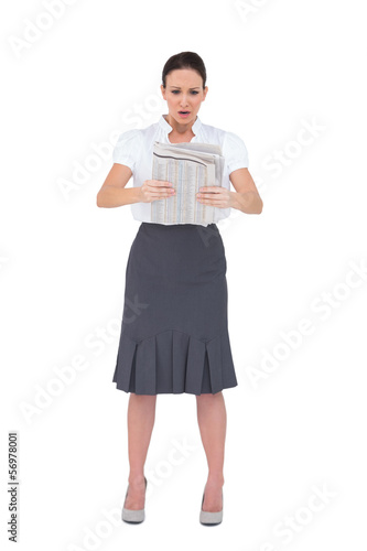 Photo: Stunned stylish businesswoman reading newspaper Stunned stylish businesswoman reading newspaper