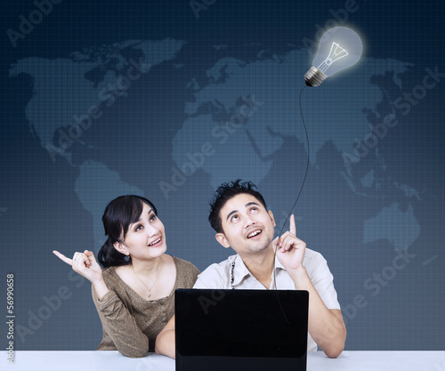 Photo: Asian couple looking at lightbulb on blue Asian couple looking at lightbulb on blue