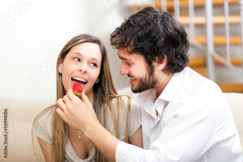 Photo: Couple sitting on the sofa while eating strawberries Couple sitting on the sofa while eating strawberries