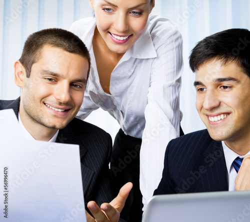 Photo: Three businesspeople working with document at office Three businesspeople working with document at office