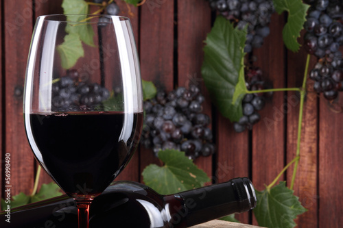 Photo: vino rosso nel bicchiere con bottiglia e grappoli d'uva vino rosso nel bicchiere con bottiglia e grappoli d'uva