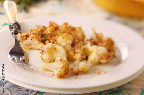 Photo: Baked cauliflower with cheese and nuts on a plate. Baked cauliflower with cheese and nuts on a plate.