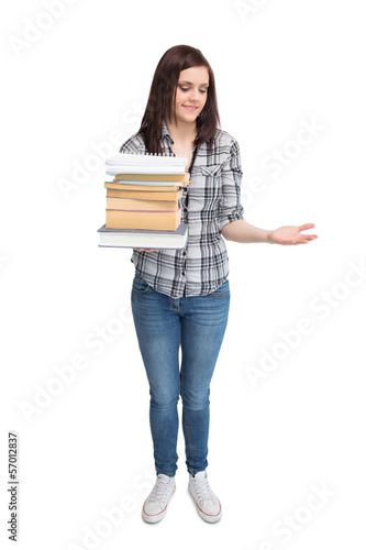 Photo: Smiling pretty student holding pile of books Smiling pretty student holding pile of books