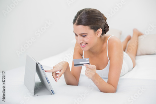 Photo: Casual young brown haired model in white pajamas shopping online Casual young brown haired model in white pajamas shopping online