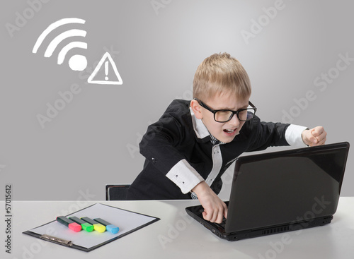 Photo: Angry boy with laptop. No wireless connection available Angry boy with laptop. No wireless connection available