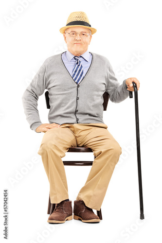 Photo: Relaxed senior man sitting on a chair and looking at camera Relaxed senior man sitting on a chair and looking at camera