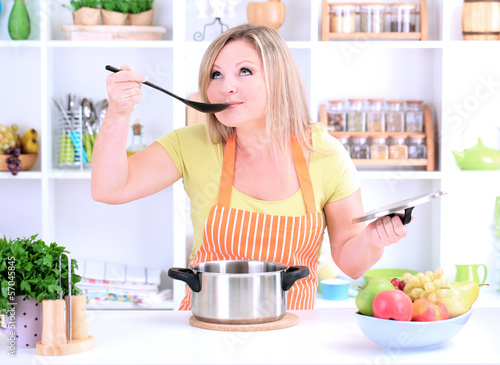 Photo: Happy smiling woman in kitchen preparing for healthy meal Happy smiling woman in kitchen preparing for healthy meal