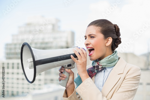 Photo: Angry smart brown haired businesswoman screaming in a megaphone Angry smart brown haired businesswoman screaming in a megaphone