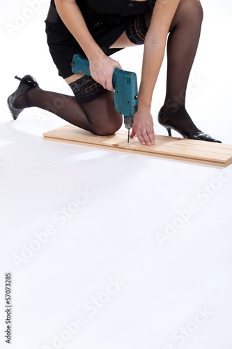 Photo: Attractive woman using drill whilst kneeling Attractive woman using drill whilst kneeling
