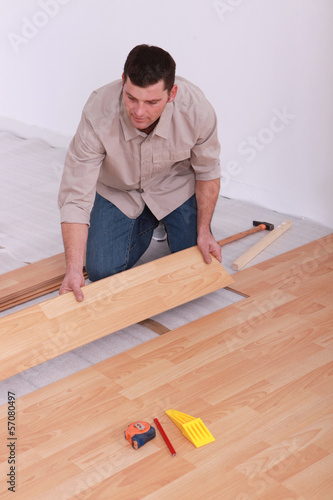 Photo: Labourer slotting together laminate flooring Labourer slotting together laminate flooring