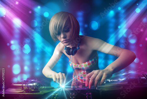 Photo: Dj girl mixing music in a club with blue and purple lights Dj girl mixing music in a club with blue and purple lights