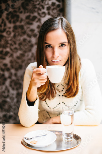 Photo: Young woman drinking cappuccino in cafe Young woman drinking cappuccino in cafe