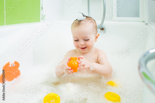 Photo: smiling baby girl taking bath and playing with toys smiling baby girl taking bath and playing with toys