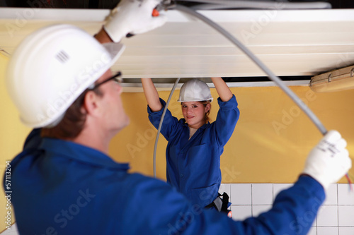 Photo: Two electricians working on the ceiling Two electricians working on the ceiling