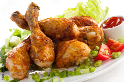 Photo: Grilled chicken legs and vegetables on white background Grilled chicken legs and vegetables on white background