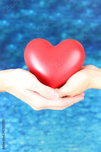 Photo: Heart in hands on blue background Heart in hands on blue background