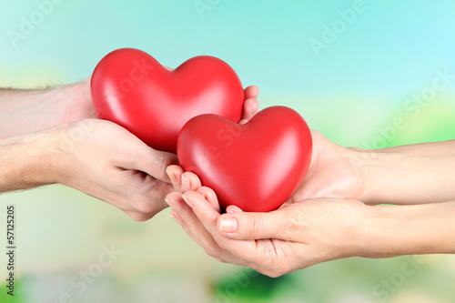 Photo: Hearts in hands on nature background Hearts in hands on nature background