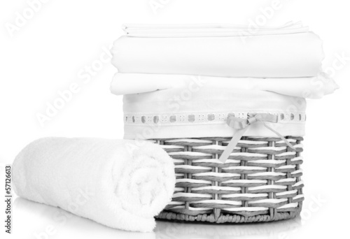 Photo: Bedding sheets in wicker basket isolated on white Bedding sheets in wicker basket isolated on white