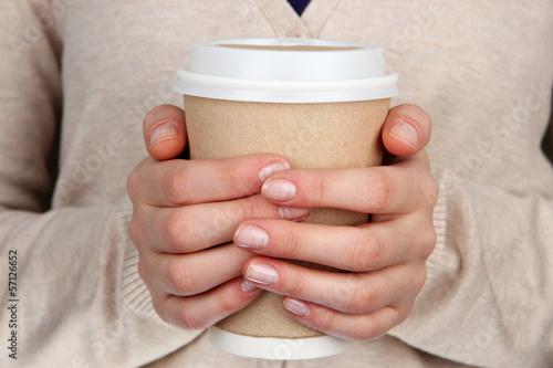 Photo: Hot drink in paper cup in hands close up Hot drink in paper cup in hands close up