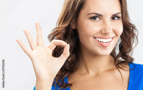 Photo: Young woman showing okay gesture, over grey Young woman showing okay gesture, over grey