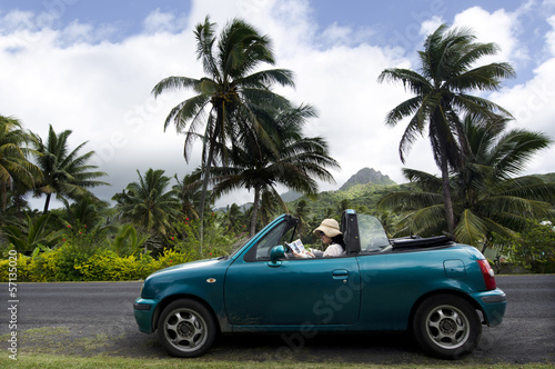 Photo: Young woman traveling by convertible car in a Pacific Island Young woman traveling by convertible car in a Pacific Island