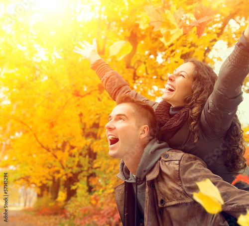 Photo: Happy Couple in Autumn Park. Fall. Family Having Fun Outdoors Happy Couple in Autumn Park. Fall. Family Having Fun Outdoors