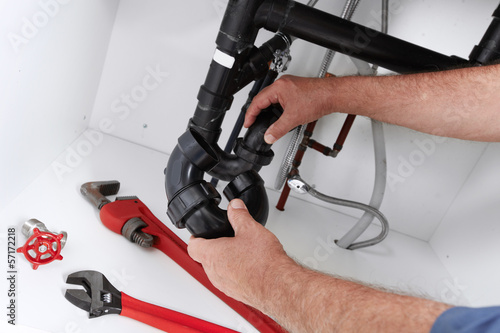 Photo: Hands of Plumber with a wrench. Hands of Plumber with a wrench.