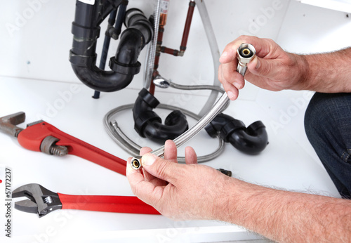 Photo: Hands of Plumber with a wrench. Hands of Plumber with a wrench.