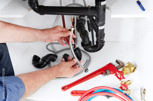 Photo: Hands of Plumber with a wrench. Hands of Plumber with a wrench.