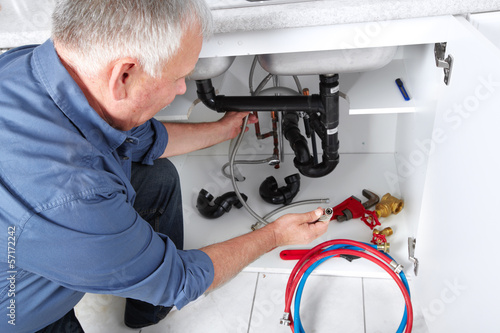 Photo: Hands of Plumber with a wrench. Hands of Plumber with a wrench.