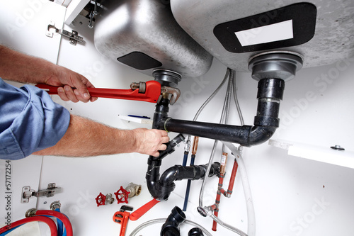 Photo: Hands of Plumber with a wrench. Hands of Plumber with a wrench.