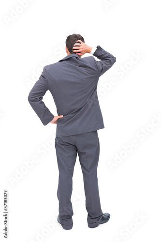 Photo: Young businessman standing back to camera scratching his head Young businessman standing back to camera scratching his head