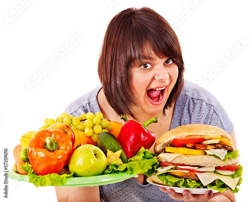 Photo: Woman choosing between fruit and hamburger. Woman choosing between fruit and hamburger.