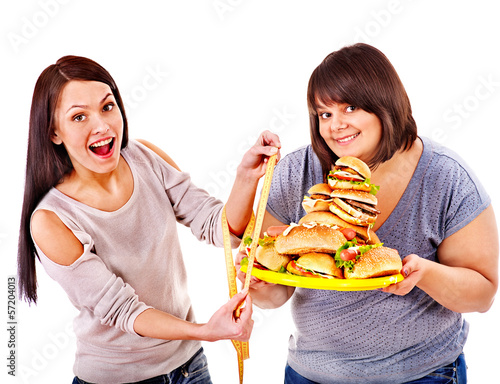Photo: Woman holding fast food and measuring tape. Woman holding fast food and measuring tape.