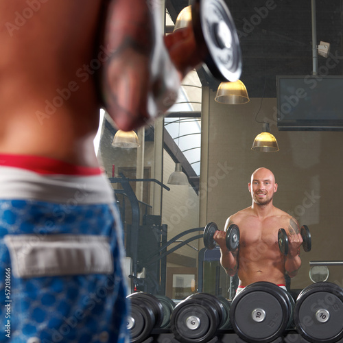 Photo: Mirror reflection of two men exercising in gym Mirror reflection of two men exercising in gym
