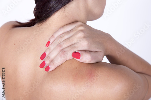 Photo: Brunette woman massaging her shoulder because it hurts. Brunette woman massaging her shoulder because it hurts.