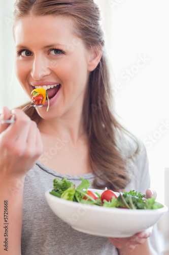 Photo: Close up of smiling woman eating salad Close up of smiling woman eating salad