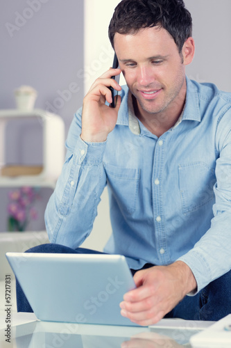 Photo: Happy casual man using tablet and phoning Happy casual man using tablet and phoning