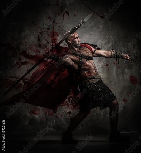 Photo: Wounded gladiator in red coat throwing spear Wounded gladiator in red coat throwing spear