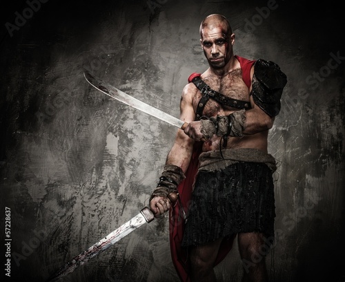 Photo: Wounded gladiator with two swords covered in blood Wounded gladiator with two swords covered in blood