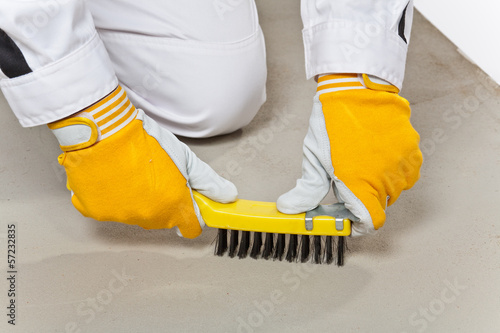 Photo: Worker with wire brush cleans the cement base Worker with wire brush cleans the cement base
