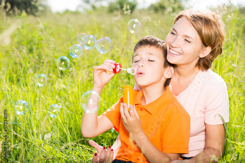 Photo: mother and son in the park blowing soap bubbles mother and son in the park blowing soap bubbles