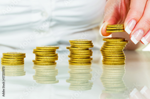 Photo: Frau mit Münzstapel beim Geld sparen Frau mit Münzstapel beim Geld sparen