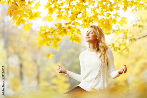 Photo: Woman meditating in autumn park Woman meditating in autumn park