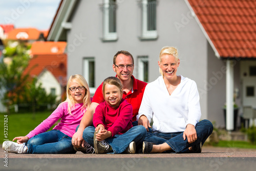 Photo: Happy family sitting in front of home Happy family sitting in front of home