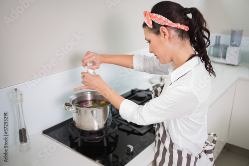 Photo: Focused gorgeous cook putting salt on vegetables Focused gorgeous cook putting salt on vegetables