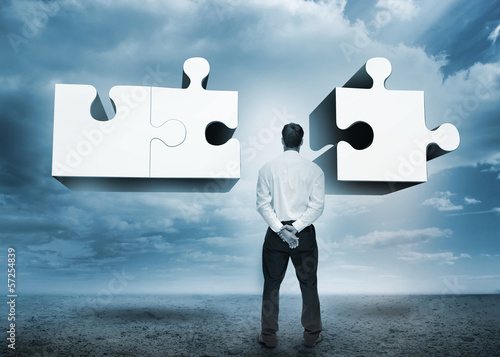 Photo: Businessman standing looking at jigsaw puzzle Businessman standing looking at jigsaw puzzle